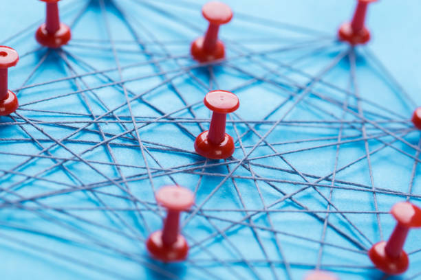 istock Small network of pins (Thumbtack)and string, An arrangement of colorful pins linked together with string on a pale blue background suggesting a network of connections. 1184109663