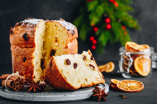 Traditional Christmas Panettone cake with dried fruits on dark stone background, copy space.