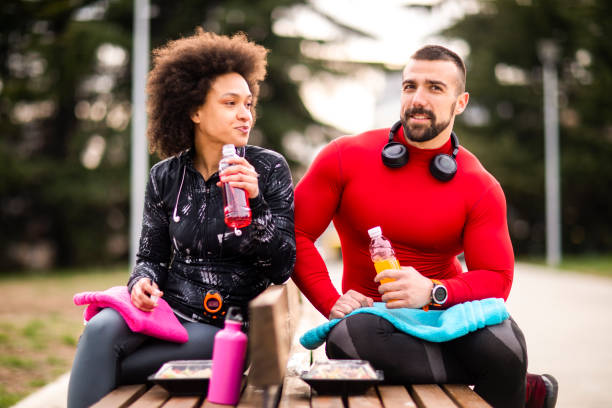 istock Two young athletes hydrating themselves while taking a break after exercising in a city park 1184136782