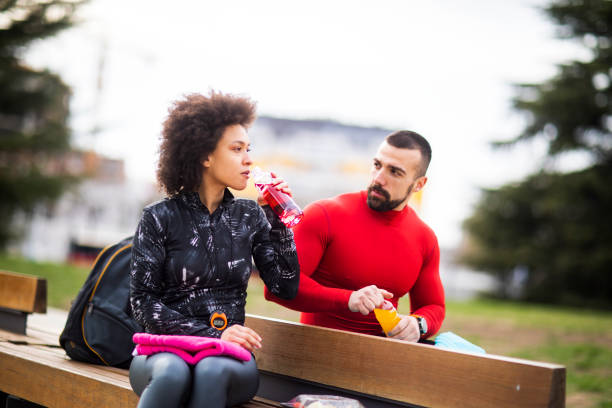 istock Young athletic couple hydrating themselves while taking a break after exercising in a city park 1184136823