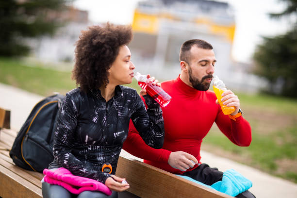 istock Young multi-ethnic athletic couple hydrating themselves while taking a break after exercising in a city park 1184137590