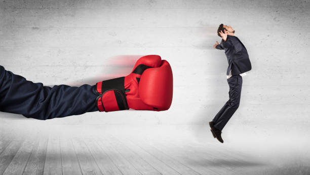 istock Arm with boxing gloves hits office worker concept 1184138125