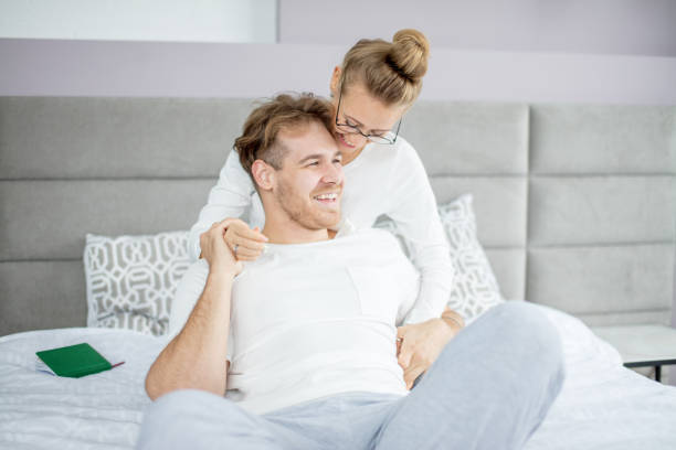 istock two young people laughing while sitting on the bed 1184139048