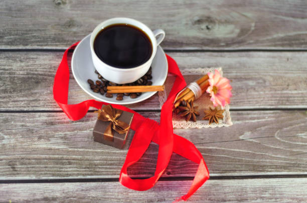 istock A beautiful composition, a cup of black coffee, decorated with grains, anise and korets, is surrounded by a bright red ribbon near the gift box. 1184140890