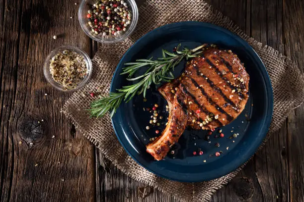 Juicy grilled pork chops with spices on a dark background