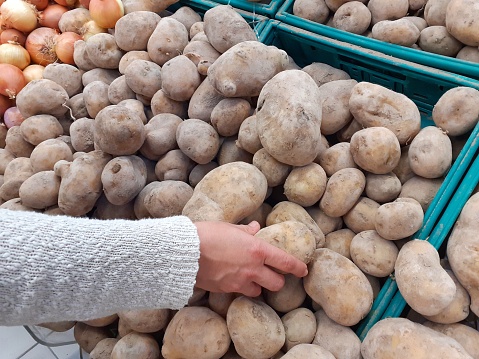 Close up view woman hand selecting potatoes in the supermarket