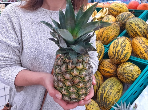 Woman holding pineapple in supermarket
