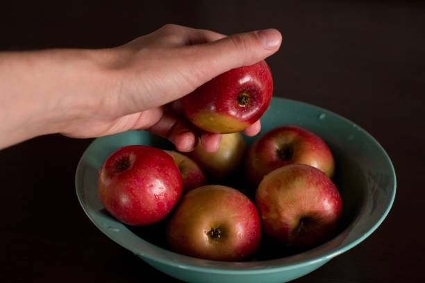 istock young woman taking an apple from a plate 1184147591