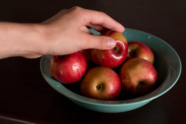 istock young woman taking an apple from a plate 1184147592
