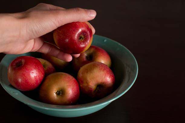 istock young woman taking an apple from a plate 1184147629