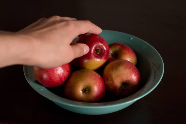 istock young woman taking an apple from a plate 1184148378