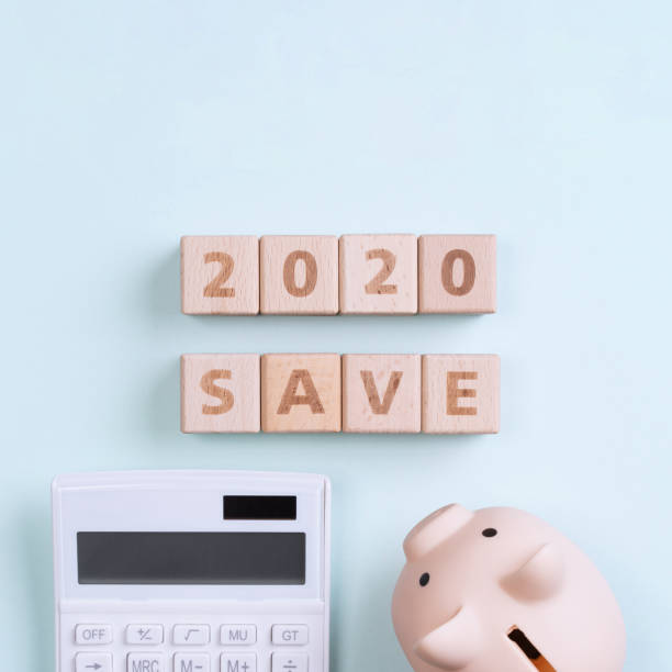 istock 2020 goal, finance plan abstract design concept, wood blocks on green table background with piggy bank and calculator, top view, flat lay, copy space. 1184150656