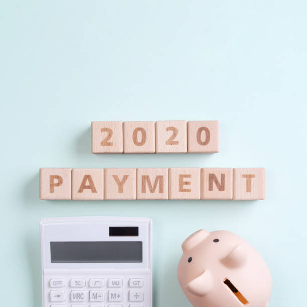 istock 2020 goal, finance plan abstract design concept, wood blocks on green table background with piggy bank and calculator, top view, flat lay, copy space. 1184150701