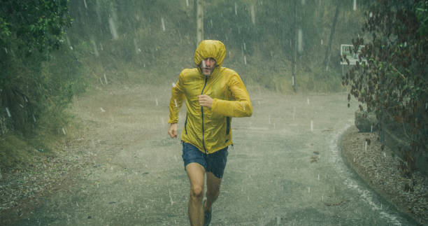 hombre atlético corriendo en condiciones climáticas extremas. granizo y lluvia - atletismo en pista masculino fotografías e imágenes de stock