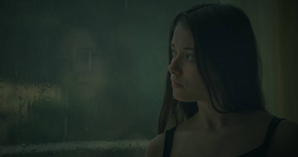 istock Pensive girl looks out the window 1184154026