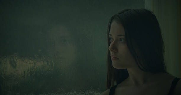 istock Pensive girl looks out the window 1184154028