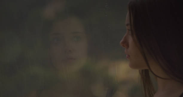 istock Pensive girl looks out the window 1184154032