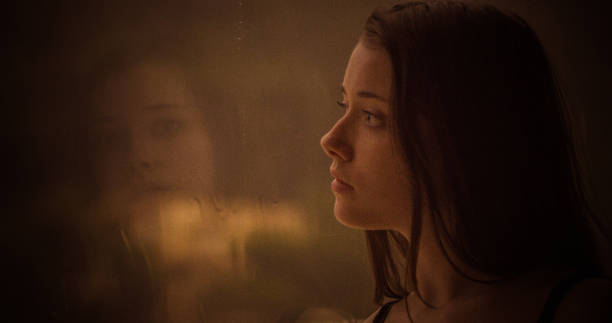 istock Pensive girl looks out the window 1184154062