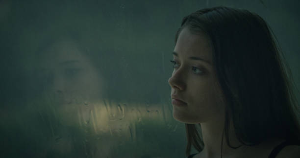 istock Pensive girl looks out the window 1184154071