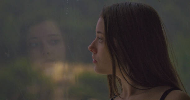 istock Pensive girl looks out the window 1184154101