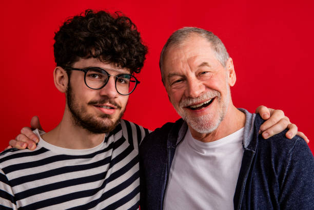 istock Young man and senior father in a studio on red background. 1184159590