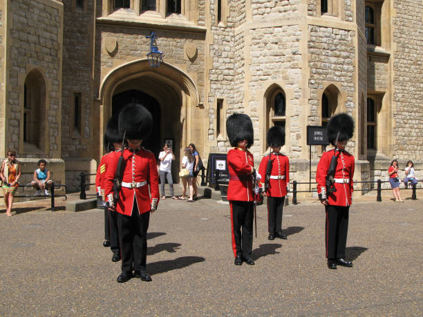 tourists look and photograph the ceremony of changing of the queen's guard in front of the  jewel house  in the tower of london, uk. - castle honor guard protection security guard imagens e fotografias de stock