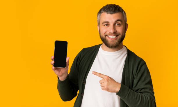 Cheerful bearded man pointing at smartphone in his hand