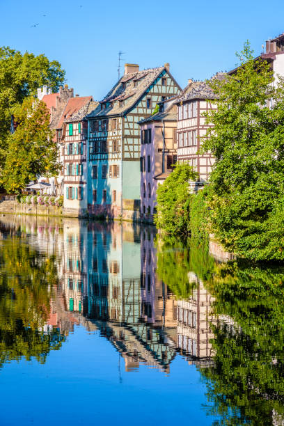 Half-timbered houses reflecting in the canal in the Petite France historic quarter in Strasbourg, France. Close-up on the half-timbered houses lining the river Ill canal in the Petite France quarter in Strasbourg, France, reflecting in the still waters under a bright sunshine. La Petite France stock pictures, royalty-free photos & images