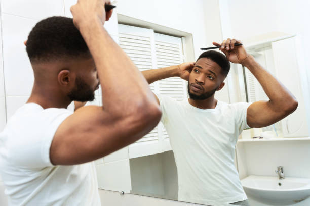 istock Young african american guy brushing his hair at bathroom 1184175432