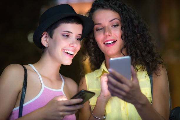 istock Young girlfriends using phone on the street 1184176100
