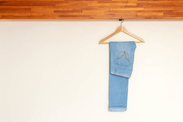 istock Light blue denim pants hanging on wood hanger on minimal open closet storage 1184176714