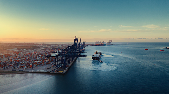 Sunrise over Felixstowe Container Port as two tugs shepherd a container ship away from the harbour wall