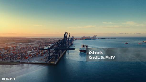 Sunrise Over Felixstowe Container Port As Two Tugs Shepherd A Container Ship Away From The Harbour Wall Stock Photo - Download Image Now