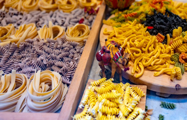 Brightly colored pasta is arranged on display at a bustling market in Old Delhi, India, capturing the vibrant culinary culture and food diversity of the region.