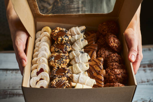 woman holding a box filled with mini christmas pastry cakes - cookie christmas shortbread food imagens e fotografias de stock