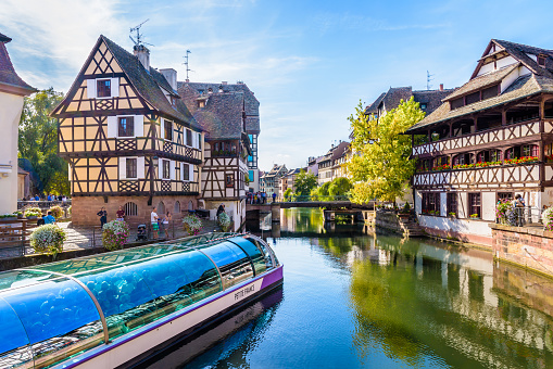 Strasbourg, France - September 14, 2019: A tour boat is cruising the river Ill canal in the Petite France quarter, a medieval district with typical half-timbered houses, very popular with tourists.