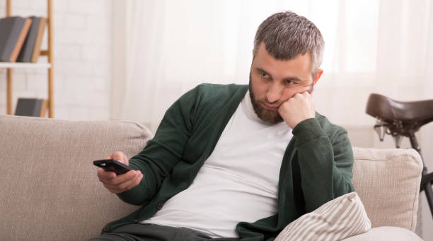 istock Bored man switching channels on TV on weekend 1184181864