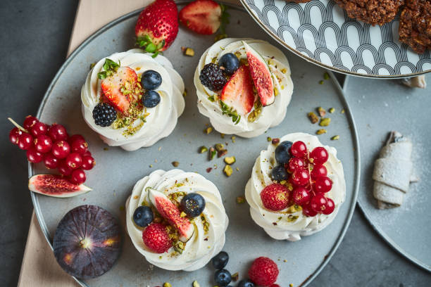 Mini Pavlova Cakes meringue dessert with berries Mini Pavlova Cakes meringue dessert with crisp crust and soft inside, top view pavlova stock pictures, royalty-free photos & images
