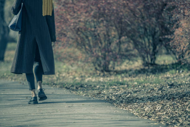 Woman walking in lonely park in autumn scenery, toned
