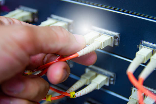 istock Technician connect fiber cable network to switch port in server room 1184183326