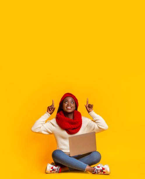 istock Excited afro girl with laptop pointing up at empty space 1184185166