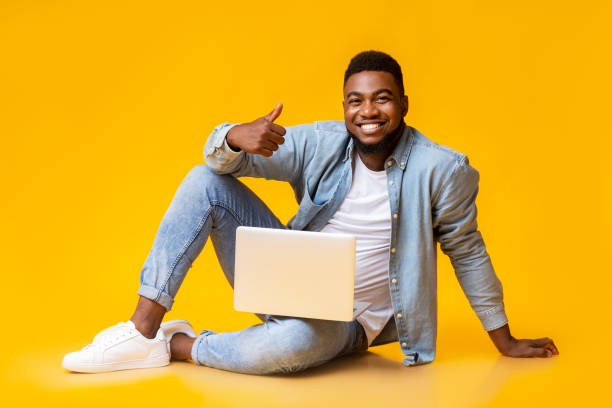 istock Happy black guy sitting with laptop and showing thumb up 1184185473