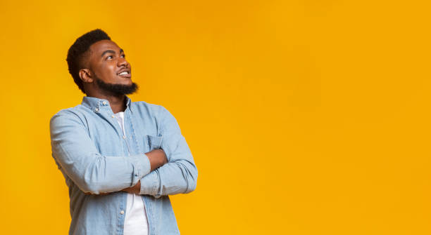 istock Interested man looking upwards at copy space on yellow background 1184187267