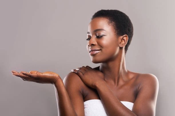 beautiful black woman demonstrating something on her open palm - moisturizer cosmetics merchandise human hand imagens e fotografias de stock