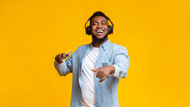 hombre negro disfrutando escuchando su música favorita en auriculares - vibrant color yellow recreational equipment red fotografías e imágenes de stock