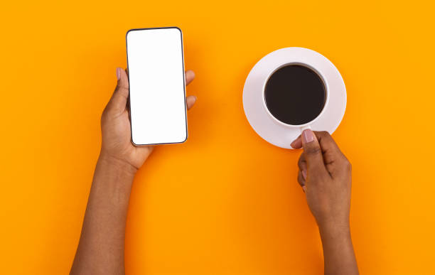 istock Black woman holding smartphone with blank screen and drinking coffee 1184188110