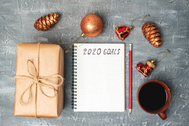 istock 2020 goals, text on the paper in notepad, New Year promises concept, gift box, coffee cup, decorations, top view 1184188521