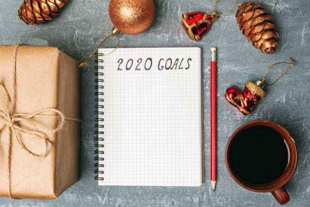 istock 2020 goals, text on the paper in notepad, New Year promises concept, gift box, coffee cup, decorations, top view 1184188531