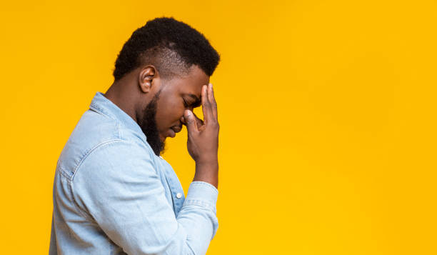istock Profile portrait of depressed black guy touching his forehead 1184188548