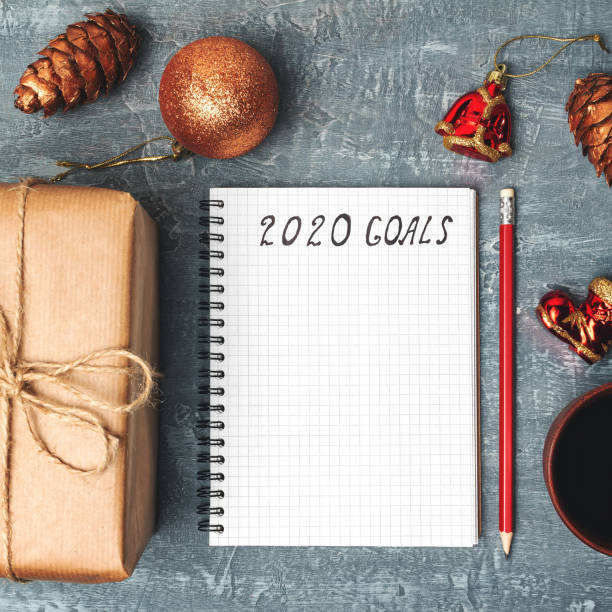 istock 2020 goals, text on the paper in notepad, New Year promises concept, gift box, coffee cup, decorations, top view 1184188649